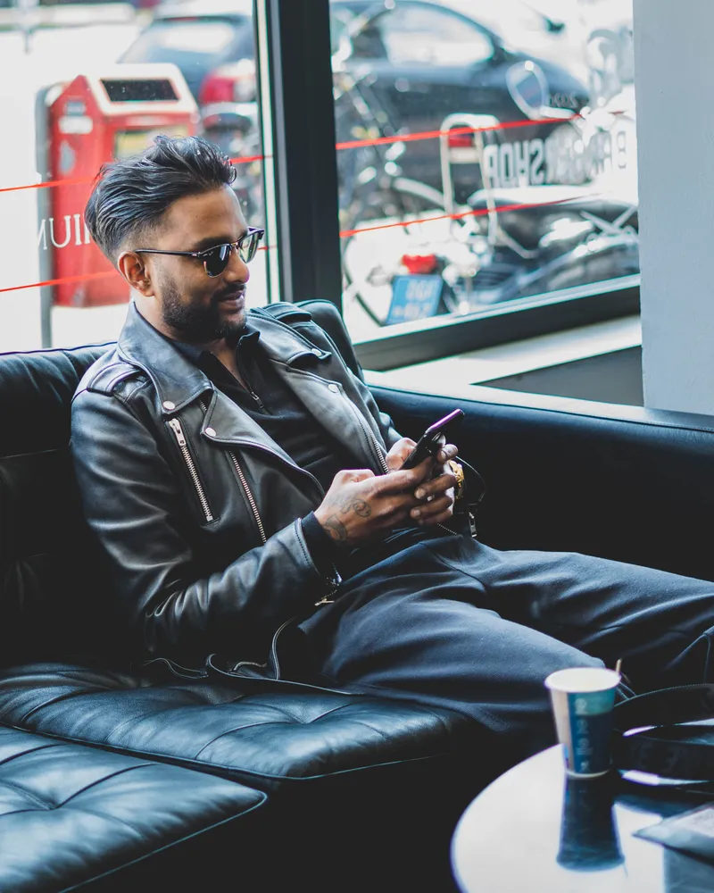 Klant ontspant met telefoon in de lounge van Matay's Barbershop Enschede