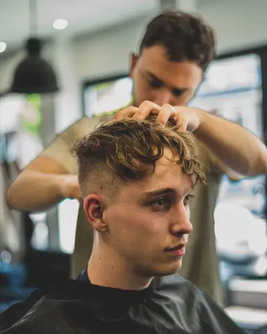 Krullend haar wordt gestyled door de barber
